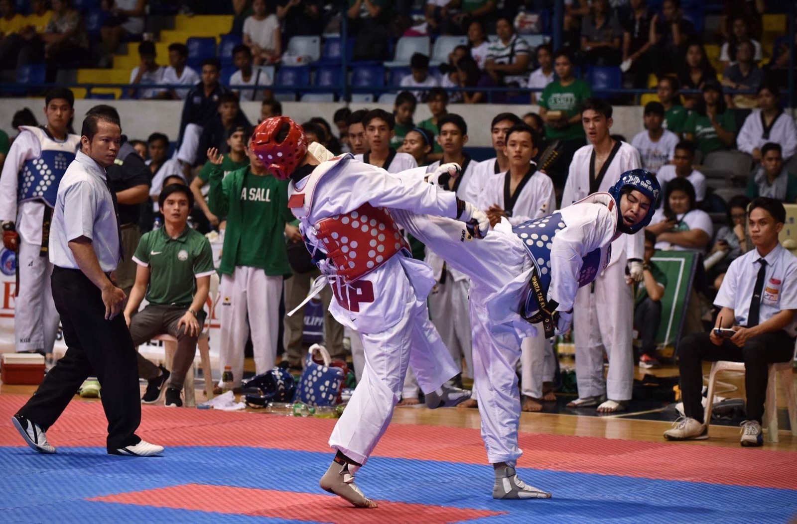 Keith Uy in blue gear throwing a kick mid-bout on the collegiate circuit in Manila