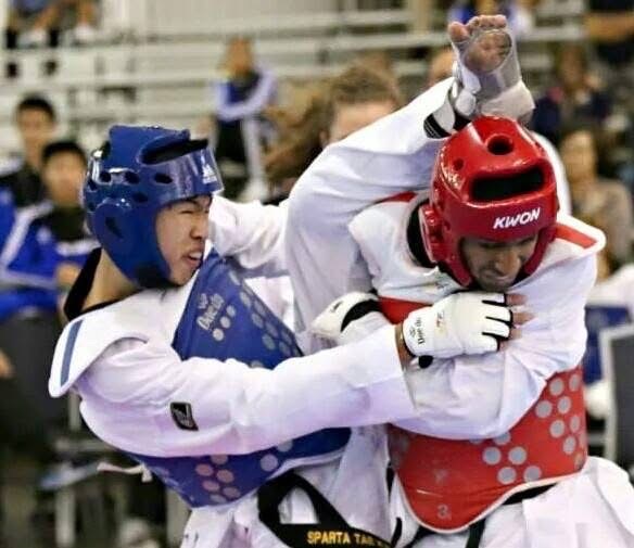 Keith Uy in blue headgear working at close range in the clinch